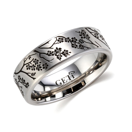 Satin titanium flat-profile silver-coloured ashes ring featuring intricately engraved cherry blossoms and branches of a tree circulating the ring.  Photographed on a white background.