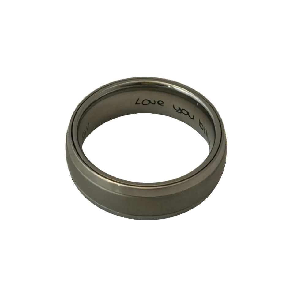 grey ashes dome ring with silver edges and hand written love you engraving on the inside of the ring on a white background