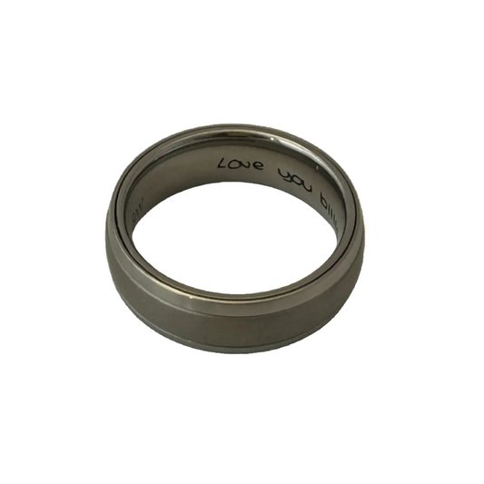 grey ashes dome ring with silver edges and hand written love you engraving on the inside of the ring on a white background
