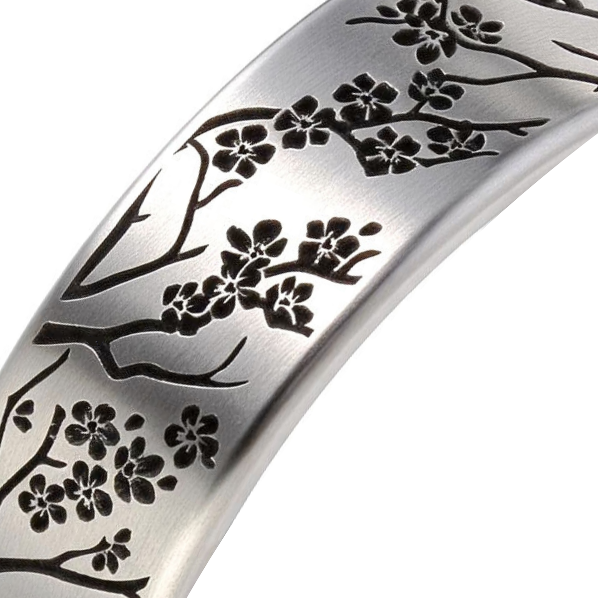 A close-up of a silver-toned metal band featuring an engraved black cherry blossom branch pattern, set against a plain white background.