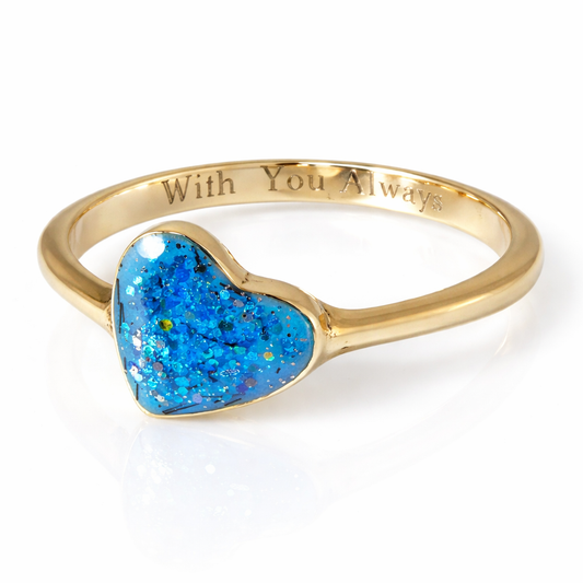 Gold ring with aqua blue glittery heart-shaped stone and engraving ‘with you always’ on a white background