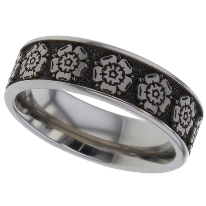 A silver-toned titanium metal band ring for cremation ashes featuring a textured black inlay with embossed floral rose motifs, shown on a plain white background.