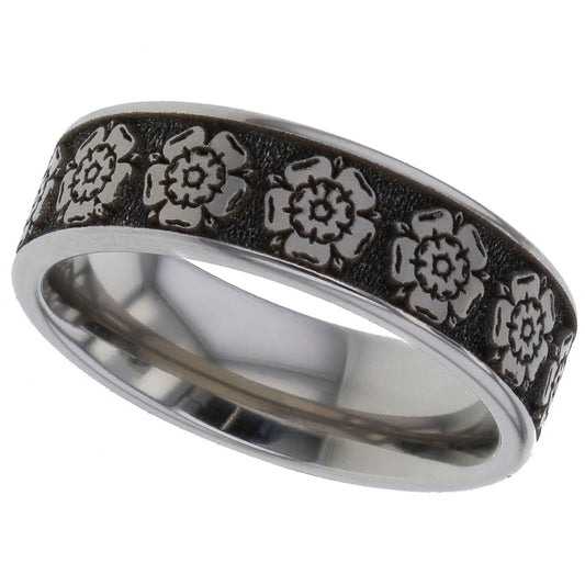 A silver-toned titanium metal band ring for cremation ashes featuring a textured black inlay with embossed floral rose motifs, shown on a plain white background.