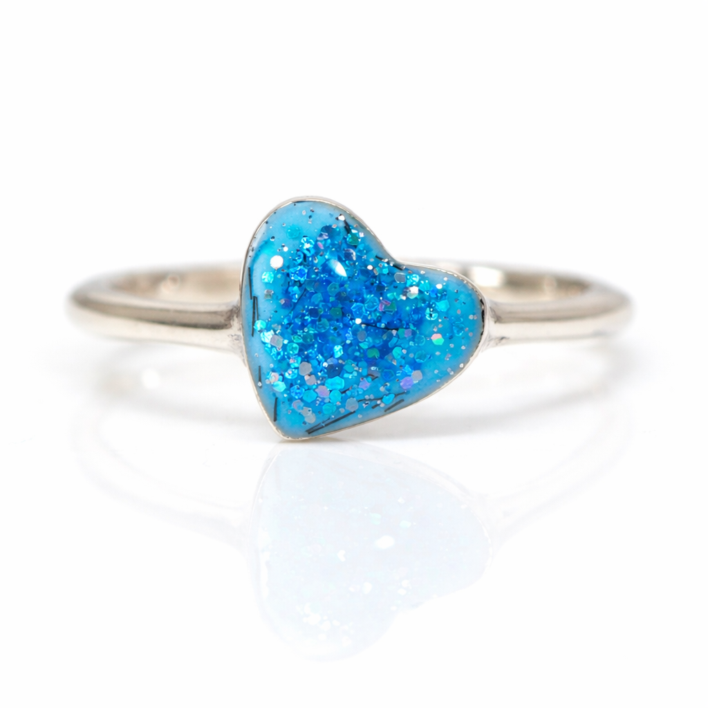 Silver slim ring band with Aqua Blue glittery heart-shaped stone on a white background