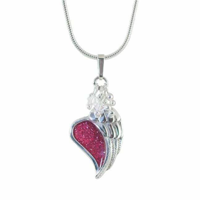 silver Angel Wing placed over a heart shaped red inlay with snake chain on a white background