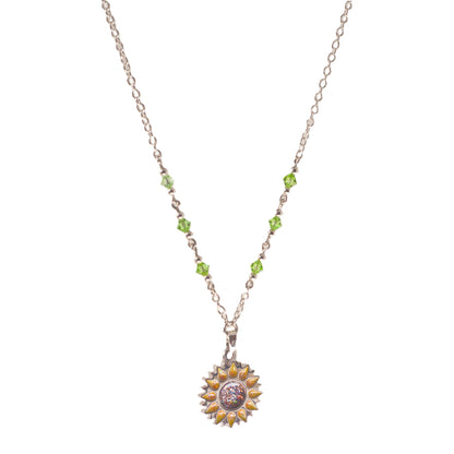 Sunflower pendant with sparkling yellow petals and a round sparkling warm orange centre on a silver long chain with green beads on a white background