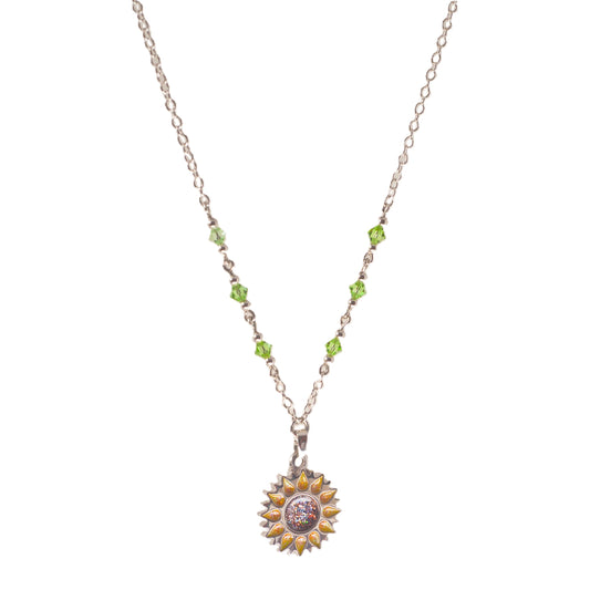 Sunflower pendant with sparkling yellow petals and a round sparkling warm orange centre on a silver long chain with green beads on a white background