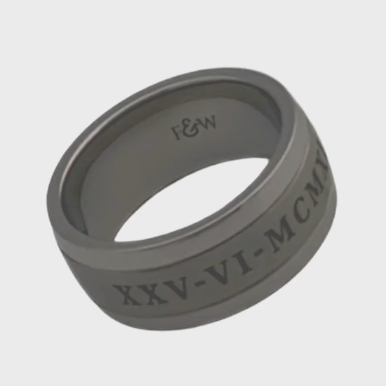 Video of titanium ashes ring with engraved date in roman numerals on a plain white background showing the ringside profile 