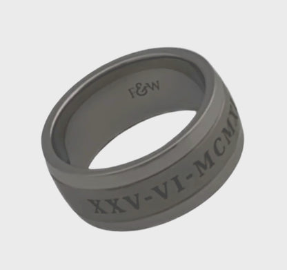 Video of titanium ashes ring with engraved date in roman numerals on a plain white background showing the ringside profile 