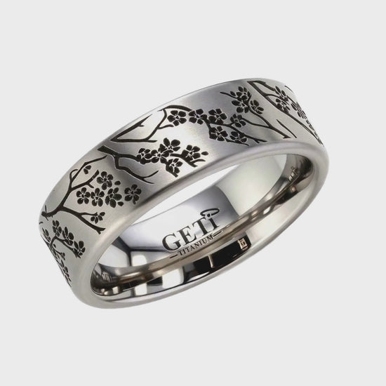 Short video clip showing a rotating silver-toned memorial ring band featuring an engraved black cherry blossom branch pattern